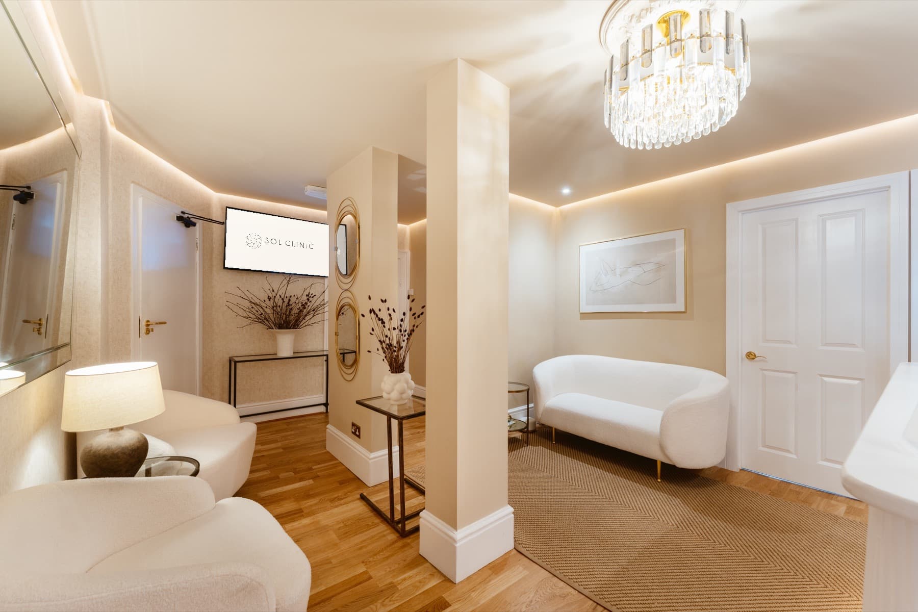 The reception lounge at Sol Clinic London, with a crystal chandelier, curved sofa and warm cream walls