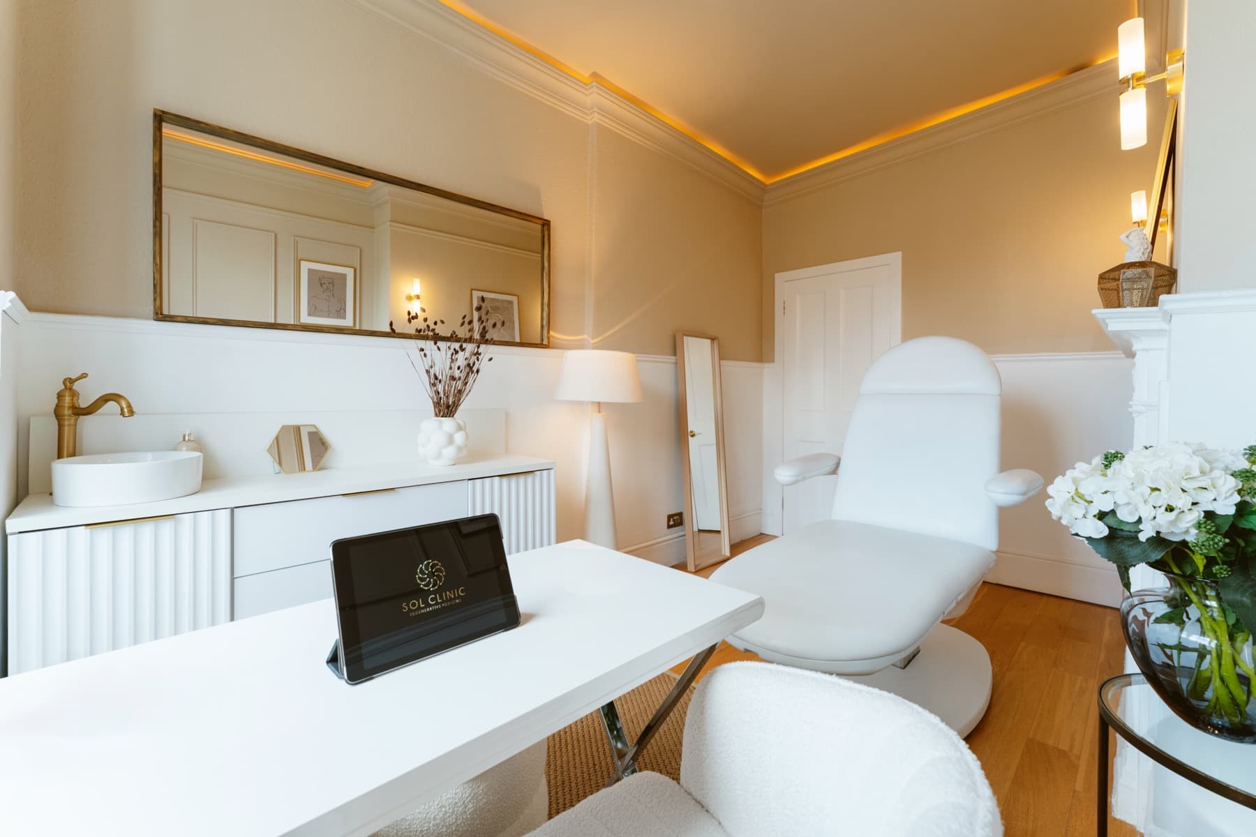 Treatment room at Sol Clinic London with a reclining chair, framed mirror and warm cream walls